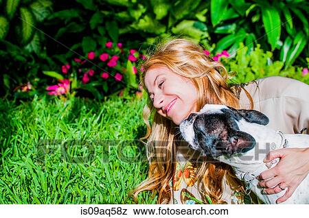 Stock Photo - Dog licking woman's face in garden. Fotosearch
