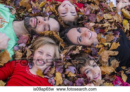 Stock Photo - "Family with heads together, lying in autumn leaves". Fotosearch