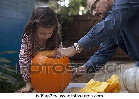 Stock Photo - Father and daughter carving pumpkin for Halloween. Fotosearch