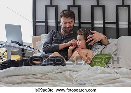 Father putting headphones on toddler daughter in bed View Large Photo Image Stock Image - Father putting headphones on toddler daughter in bed. Fotosearch