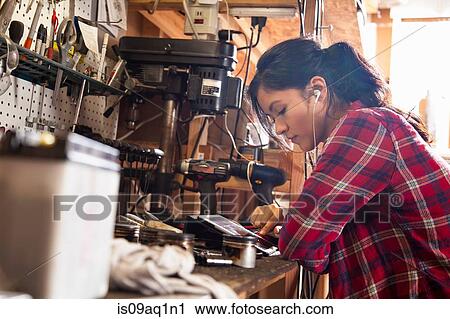 "Female mechanic in workshop, using digital tablet, wearing earphones" View Large Photo Image Stock Image - "Female mechanic in workshop, using digital tablet, wearing earphones". Fotosearch