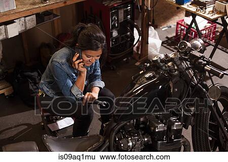Stock Photograph - Female mechanic using mobile phone in workshop. Fotosearch