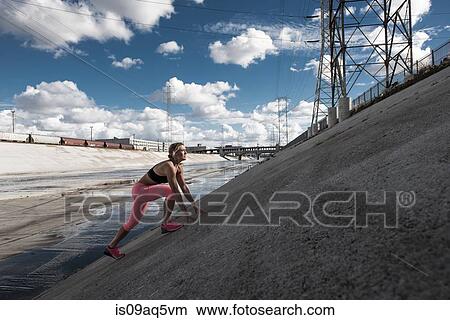 Picture - "Female runner moving up steep river aquaduct, Los Angeles, California, USA". Fotosearch