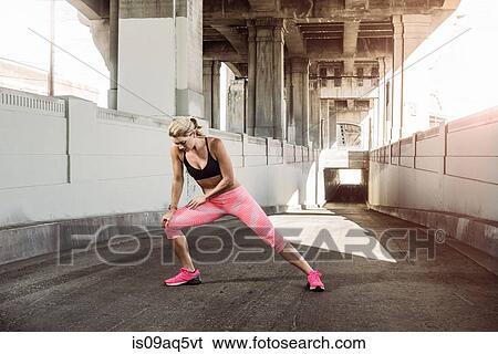 Female runner stretching under city bridge View Large Photo Image Stock Photograph - Female runner stretching under city bridge. Fotosearch