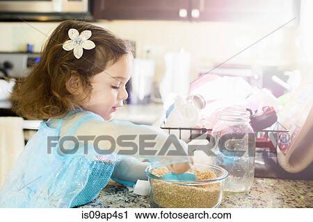 Stock Image - Female toddler mixing baking ingredients at kitchen counter. Fotosearch