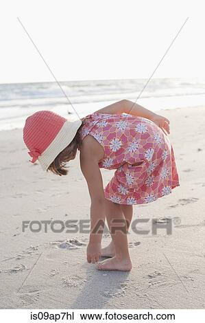 Stock Image - Girl exploring on the beach at sunset. Fotosearch