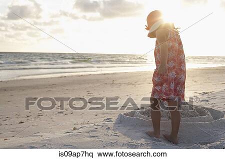 Stock Photography - Girl exploring on the beach at sunset. Fotosearch