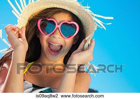 Stock Image - Girl wearing sunglasses and straw hat. Fotosearch