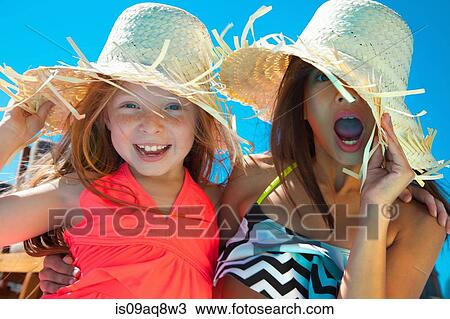 Stock Image - Girls wearing sunglasses and straw hats. Fotosearch