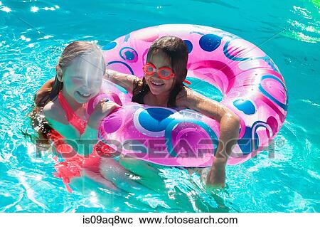 Stock Image - Girls with inflatable ring in swimming pool. Fotosearch