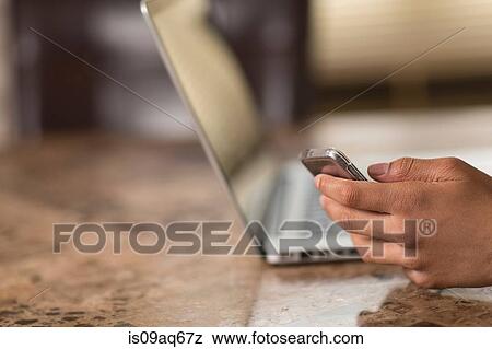 Stock Photo - Hand of teenage boy at dining table texting on smartphone. Fotosearch