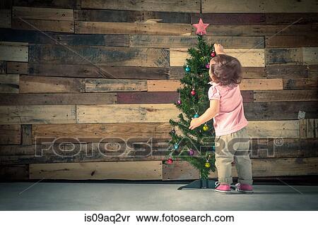 Stock Photography - Little girl decorating Christmas tree. Fotosearch