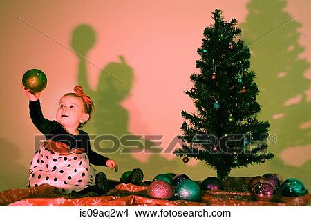 Picture - Little girl holding a christmas bauble. Fotosearch