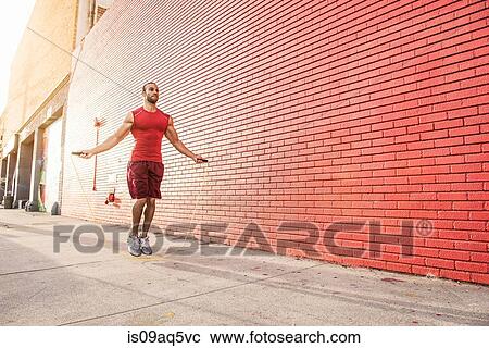 Male runner skipping on sidewalk View Large Photo Image Stock Image - Male runner skipping on sidewalk. Fotosearch