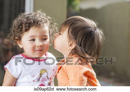 Stock Image - Male toddler kissing female toddler on cheek in back yard. Fotosearch
