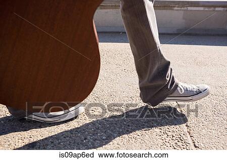"Man carrying guitar, view of legs" View Large Photo Image Stock Image - "Man carrying guitar, view of legs". Fotosearch