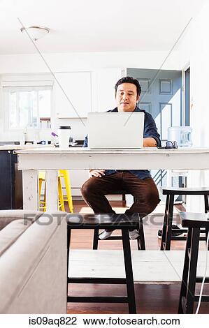 Mature businessman typing on laptop at kitchen table View Large Photo Image Stock Image - Mature businessman typing on laptop at kitchen table. Fotosearch