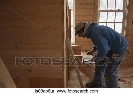 Stock Photography - Mature man building wooden staircase in house. Fotosearch
