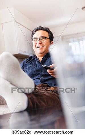 Mature man on sofa watching tv with remote control View Large Photo Image Stock Image - Mature man on sofa watching tv with remote control. Fotosearch