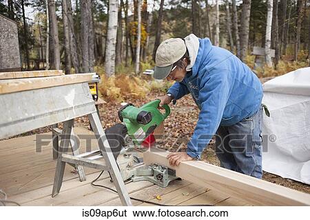 Mature man sawing plank of wood outside house View Large Photo Image Stock Photograph - Mature man sawing plank of wood outside house. Fotosearch