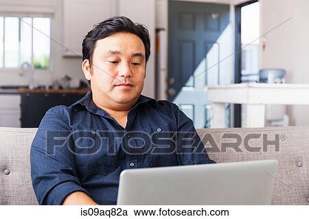 Mature man working on laptop on sofa View Large Photo Image Stock Image - Mature man working on laptop on sofa. Fotosearch