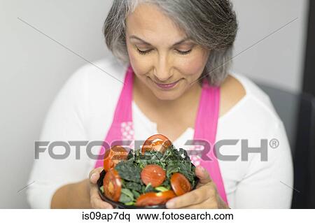 Mature woman holding bowl of tomatoes and kale View Large Photo Image Stock Photography - Mature woman holding bowl of tomatoes and kale. Fotosearch