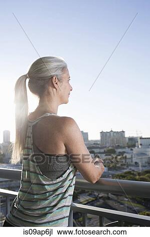 Mature woman in sports clothing leaning against city balcony View Large Photo Image Stock Image - Mature woman in sports clothing leaning against city balcony. Fotosearch