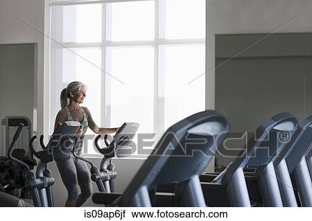 Mature woman on gym machine using touchscreen control View Large Photo Image Stock Image - Mature woman on gym machine using touchscreen control. Fotosearch