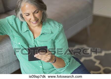 "Mature woman sitting on floor next to sofa, using digital tablet" View Large Photo Image Stock Image - "Mature woman sitting on floor next to sofa, using digital tablet". Fotosearch