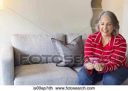 "Mature woman sitting on sofa, using smartphone" View Large Photo Image Stock Image - "Mature woman sitting on sofa, using smartphone". Fotosearch