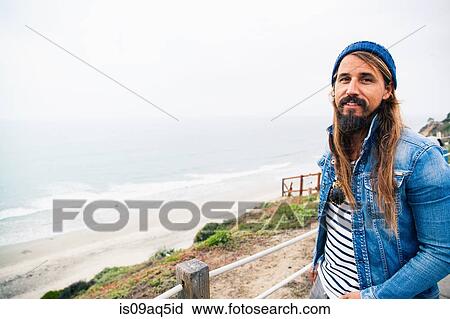 Mid adult man by sea looking at camera View Large Photo Image Stock Image - Mid adult man by sea looking at camera. Fotosearch