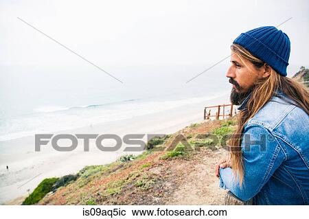 Stock Image - Mid adult man looking at coastal view. Fotosearch