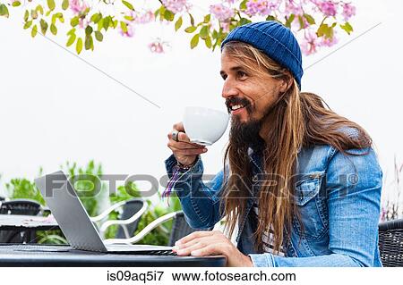 Mid adult man with coffee using laptop View Large Photo Image Stock Photo - Mid adult man with coffee using laptop. Fotosearch