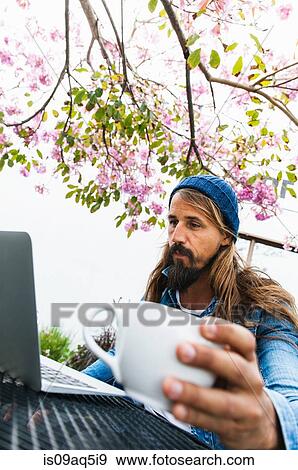 Mid adult man with coffee using laptop View Large Photo Image Stock Photo - Mid adult man with coffee using laptop. Fotosearch