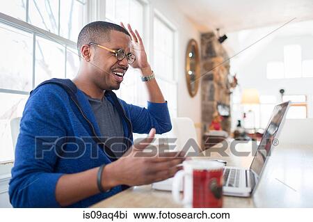 Mid adult man with hands raised in disbelief using laptop at kitchen counter View Large Photo Image Stock Image - Mid adult man with hands raised in disbelief using laptop at kitchen counter. Fotosearch