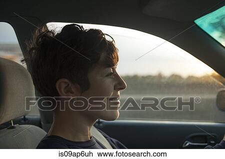 Stock Image - Mid adult woman driving in car. Fotosearch