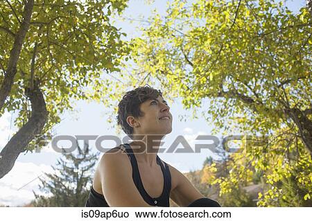 Mid adult woman gazing up at forest trees View Large Photo Image Picture - Mid adult woman gazing up at forest trees. Fotosearch