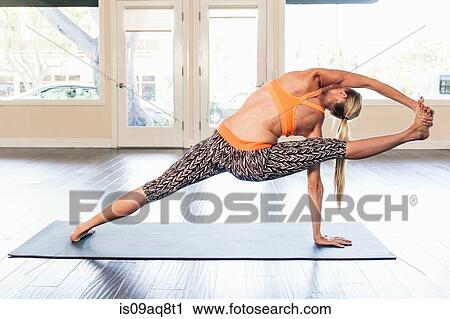 Mid adult woman in yoga position holding leg View Large Photo Image Stock Image - Mid adult woman in yoga position holding leg. Fotosearch