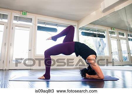 Stock Image - Mid adult woman in yoga position. Fotosearch