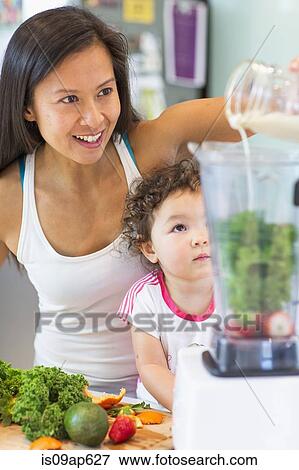 Mid adult woman making smoothie for toddler niece in kitchen View Large Photo Image Stock Photo - Mid adult woman making smoothie for toddler niece in kitchen. Fotosearch