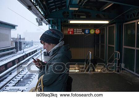Mid adult woman standing at train station using mobile phone View Large Photo Image Stock Photography - Mid adult woman standing at train station using mobile phone. Fotosearch