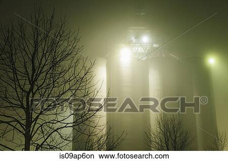 "Misty view of industrial storage tanks and silhouetted trees at night, Seattle, Washington, USA" View Large Photo Image Picture - "Misty view of industrial storage tanks and silhouetted trees at night, Seattle, Washington, USA". Fotosearch