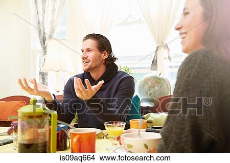 Over shoulder view of young man explaining at breakfast table View Large Photo Image Picture - Over shoulder view of young man explaining at breakfast table. Fotosearch