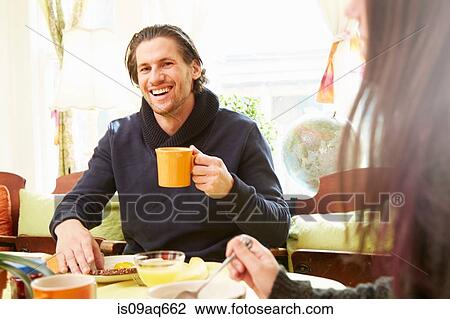 Over shoulder view of young man drinking coffee at breakfast table View Large Photo Image Stock Image - Over shoulder view of young man drinking coffee at breakfast table. Fotosearch