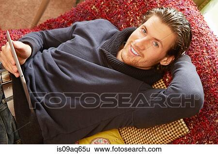 Stock Photograph - Overhead portrait of young man reclining on sofa. Fotosearch