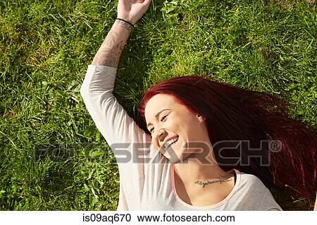 Overhead view of young woman lying on grass laughing View Large Photo Image Stock Image - Overhead view of young woman lying on grass laughing. Fotosearch