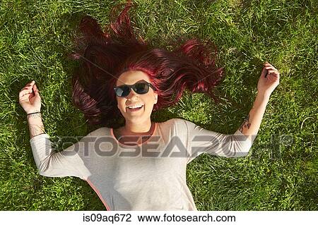 Overhead view of young woman with red hair lying on grass View Large Photo Image Stock Image - Overhead view of young woman with red hair lying on grass. Fotosearch
