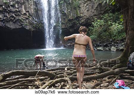 Stock Photograph - People swimming by waterfall. Fotosearch