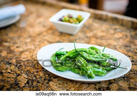 Picture - Plate with green chilli appetizer on restaurant table. Fotosearch