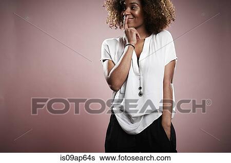 Stock Photograph - Portrait of a young woman with finger on lips. Fotosearch